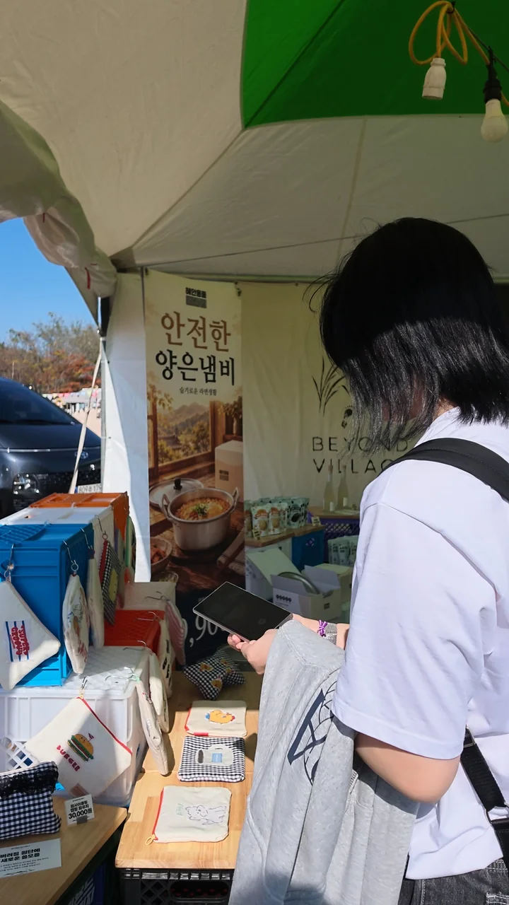부스 진열대 앞에서 파우치를 살피는 학생